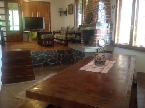 sala de estar con mesa de madera y chimenea en Къща за гости Ива, 