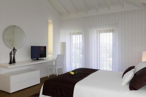 a white bedroom with a bed and a mirror at Cantinho do Cantador in Riba de Mouro
