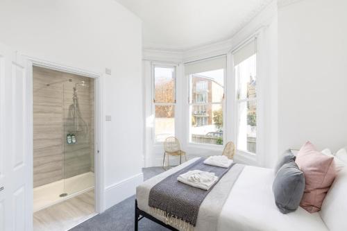 a white bedroom with a bed and a walk in shower at Lovely, modern & spacious 1-bed flat central Hove in Brighton & Hove