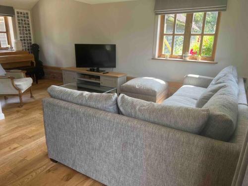 a living room with a couch and a flat screen tv at Beautiful 2 bed Oast - 15 acre farm - Tunbridge Wells in Royal Tunbridge Wells