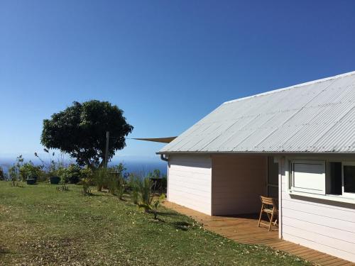 ein weißer Schuppen mit einem Tisch und Stühlen daneben in der Unterkunft Gîte rural _ vue Océan _ des bateaux dans le ciel in Saint-Denis