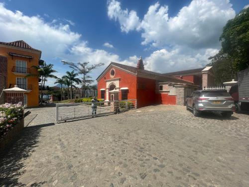 a red house with a car parked in front of it at Villa Venecia Colonial in Venecia