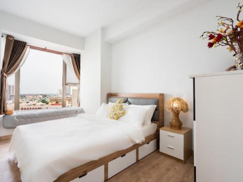 a white bedroom with a large bed and a window at Lalana Apartment in Ho Chi Minh City