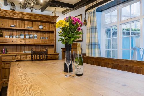 un tavolo con due bottiglie di vino e un vaso di fiori di Historic Osborne House very close to the beach a Looe