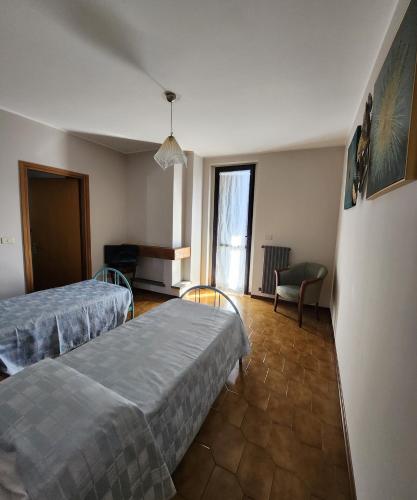 una camera ospedaliera con due letti e una sedia di Hotel Mistrello di Savoia a Borgo Val di Taro