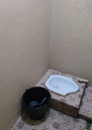 a bathroom with a toilet and a black bucket at Reza Kost 
