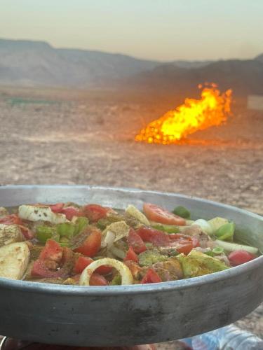 a pan filled with vegetables in front of a fire at - Trekking from Dana to Petra in Dana