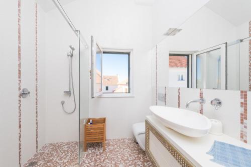 a white bathroom with a sink and a shower at Maki Exclusive Apartments in Hvar