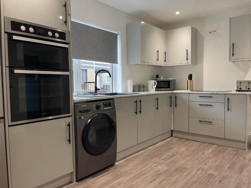 a kitchen with white cabinets and a washer and dryer at The great escape in Skerries