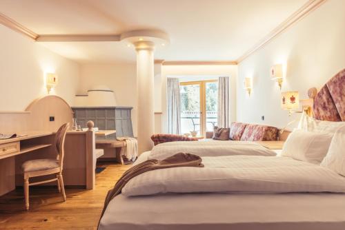 a bedroom with two beds and a desk and a kitchen at Hotel Neuhintertux 4 Sterne superior in Tux