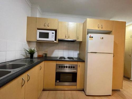 a kitchen with a white refrigerator and a microwave at City Apartment - Free Parking, 3 bedrooms and 2 bathrooms in Adelaide