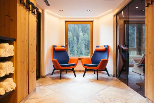 two orange chairs in a room with a window at Hotel Neuhintertux 4 Sterne superior in Tux