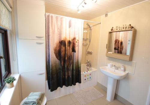 a bathroom with a shower curtain and a sink at Moo Cow Cottage Self Catering in Oakham