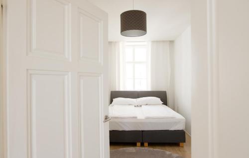 ウィーンにあるMINIMALISTIC STUDIO NEAR NASCHMARKTの白いシーツと窓のあるベッドのある寝室