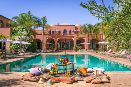 a swimming pool with people laying on the ground in front of a house at Palais Hassoun Marrakech in Oulad Snaguia
