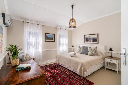 a bedroom with a bed and a table at Corner House - Knysna in Knysna