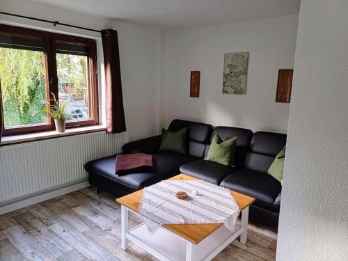 ein Wohnzimmer mit einem schwarzen Sofa und einem Tisch in der Unterkunft Große Ferienwohnungen 5 - 8 "Pumphut's Scheune" in Lengenfeld