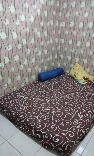 ein braunes Bett mit einem Kissen darüber in der Unterkunft Reza Kost 