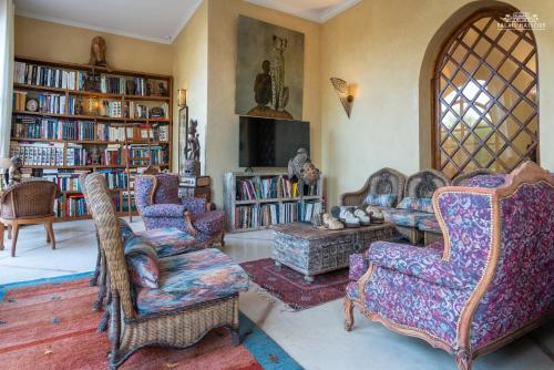 a living room with couches and a tv and books at Palais Hassoun Marrakech in Oulad Snaguia