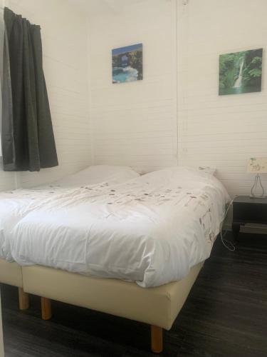 uma cama branca num quarto com duas fotografias na parede em Het molenhuisje em Winsum