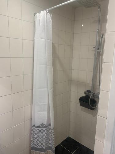 a shower with a white curtain in a bathroom at Het molenhuisje in Winsum