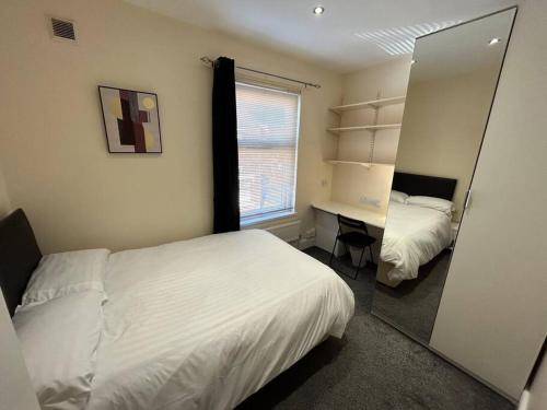 1 dormitorio con 2 camas, escritorio y ventana en Practical and Spacious Property, en Stoke on Trent