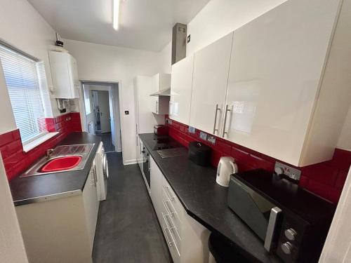 una cocina con armarios rojos y blancos y fregadero en Practical and Spacious Property, en Stoke on Trent