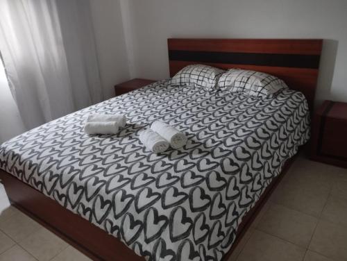 a bed with a black and white comforter with towels on it at Cantinho do Sol in Grândola