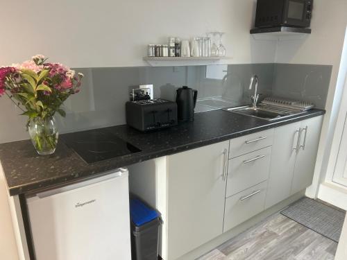 a kitchen with white cabinets and a black counter top at 29a in Downham Market
