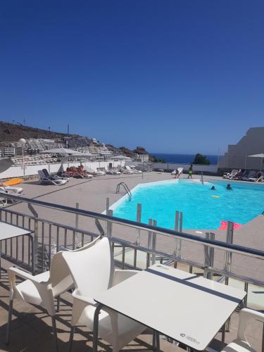 a large swimming pool with white chairs and avisorvisor at Relax Arimar Apartment Puerto Rico in Puerto Rico de Gran Canaria