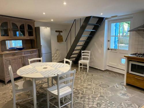 a kitchen with a table and chairs and a staircase at Montjoïa Le gîte bleu in Le Thor