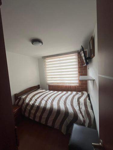 a small bedroom with a bed and a window at El Bosque in Bogotá