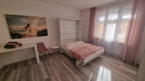 a bedroom with a bed and a desk and a window at Apartman Centrum Mudronova in Košice