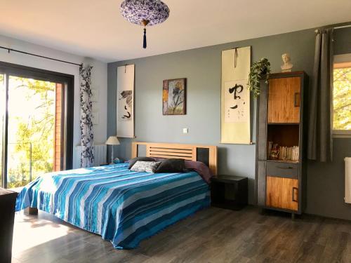 a bedroom with a bed with a blue comforter at 116 Espigarie in Le Vigan