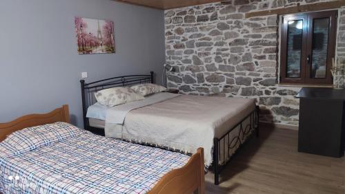 a bedroom with two beds and a stone wall at ΜΑΡΙΓΟΥΛΑΜ in Kalesménon