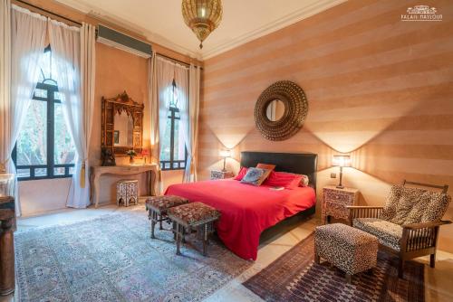 a bedroom with a red bed and chairs and a mirror at Palais Hassoun Marrakech in Oulad Snaguia
