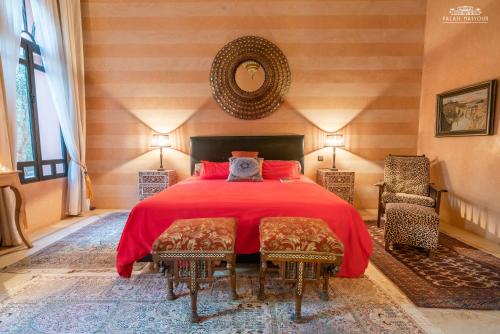 a bedroom with a bed with a red blanket and chairs at Palais Hassoun Marrakech in Oulad Snaguia