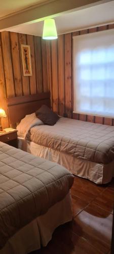 a bedroom with two beds and a window in it at Cabañas cerca de Valdivia, en San José de la Mariquina in San José de la Mariquina