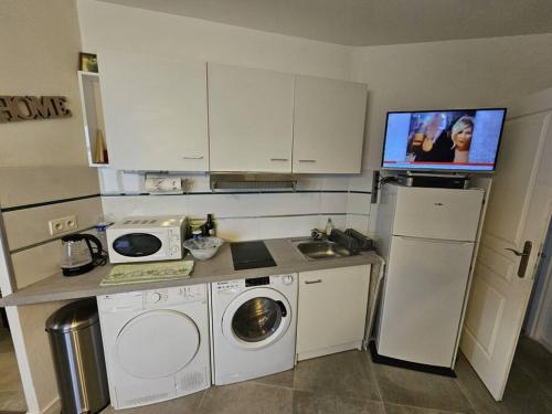 eine Küche mit einer Waschmaschine und einem TV an der Wand in der Unterkunft Studio bien équipé proche mer in Montpellier