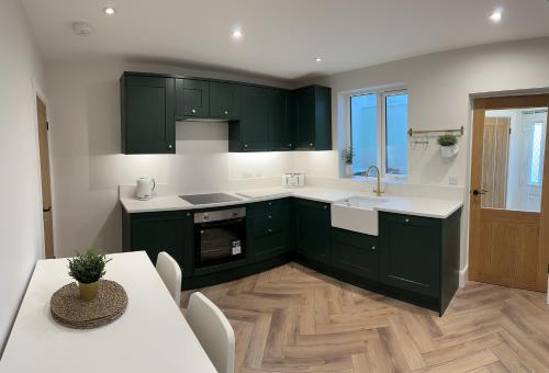 a kitchen with green cabinets and a table and a sink at Ivy Cottage Derbyshire in South Wingfield