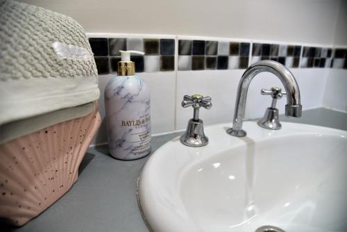 a bathroom counter with a sink and a bottle of soap at Madora Bay Beach House in Mandurah