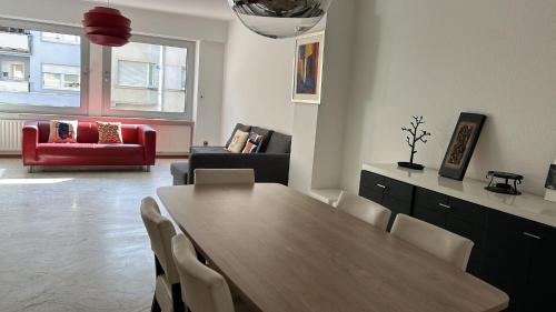 uma sala de estar com uma mesa de madeira e um sofá vermelho em City Center Cosy Three Beds em Luxemburgo