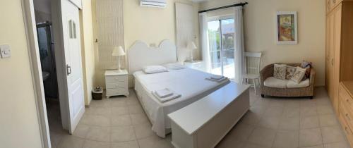 a white bedroom with a bed and a chair at Ozankoy Villa in Kyrenia