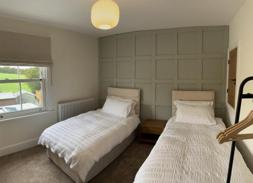 a bedroom with two beds and a window at Ivy Cottage Derbyshire in South Wingfield