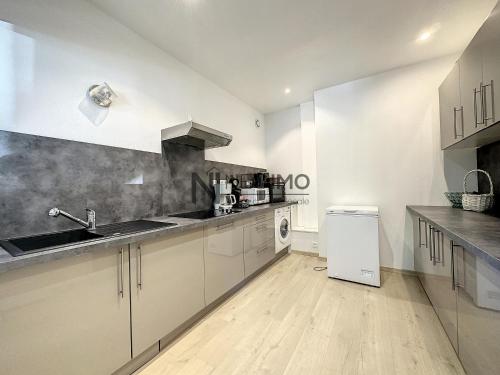 une cuisine avec des armoires blanches, un évier et un lave-vaisselle dans l'établissement lac et montagne Gerardmer, à Gérardmer