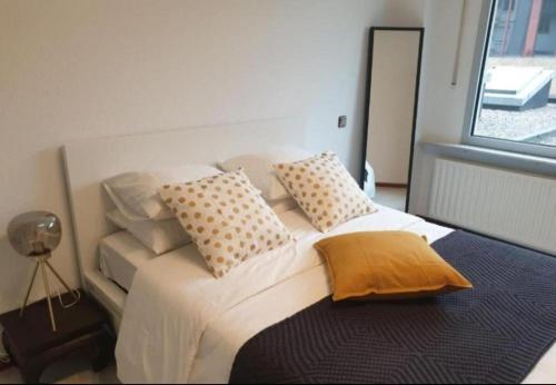 um quarto com uma cama com almofadas e uma janela em City Center Cosy Three Beds em Luxemburgo