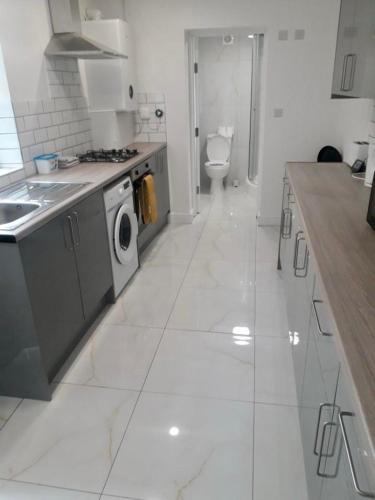 a white kitchen with a sink and a washing machine at Catherine 5 bedroom house in Crewe