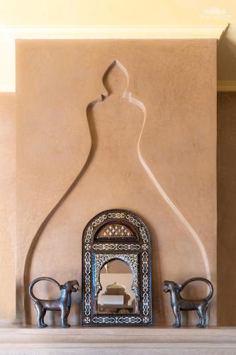 a shelf with a mirror and two statues on it at Palais Hassoun Marrakech in Oulad Snaguia