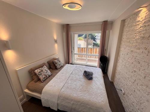 1 dormitorio con cama y ventana en Les Arènes - Cannes centre, Charmant 2 pièces récemment rénové de 45 m2 avec sa terrasse de 10 m2 en Cannes