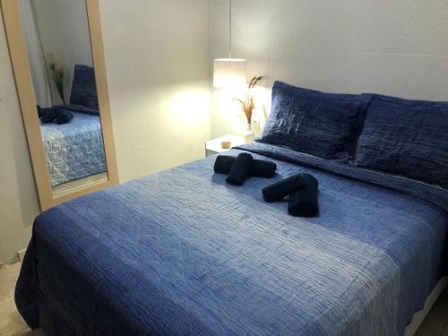 a bedroom with a blue bed with a mirror at Casa Completa Prox Centro de Pipa in Pipa